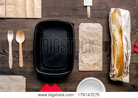food delivery service workdesk with paper bags and sandwich on wooden background top view