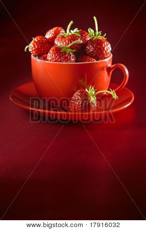 Frische Erdbeeren auf einem Teller und einer Tasse saftige Erdbeeren