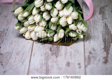 white tulips on white wooden background pink ribbon