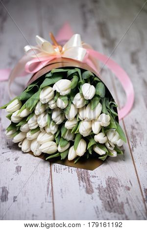 white tulips on white wooden background pink ribbon