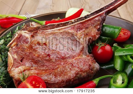 cibo di carne: manzo alla griglia di ricambio rib sul piatto scuro con pepe timo e pomodoro sul tavolo di legno