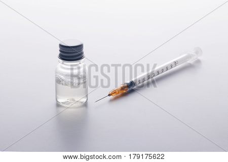One Syringe And A Mysterious Vial On A White Table.