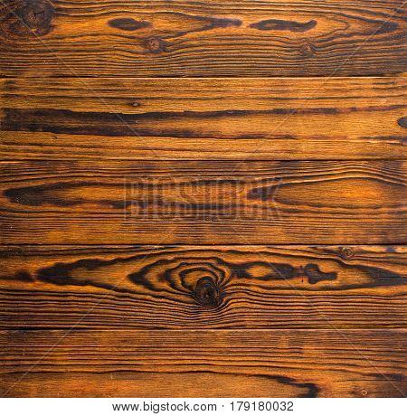 Horizontally disposed burnt and stained wood boards with knots texture or background. Red and brown. Artificially aged.