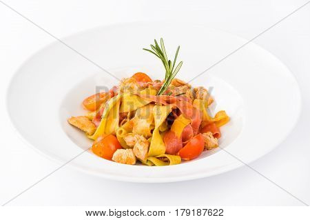 Pasta with chicken tomatoes and rosemary in a white plate on a light background