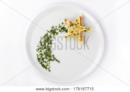 Rice with vegetables on a white plate is laid out in the shape of a star with a plume of dill