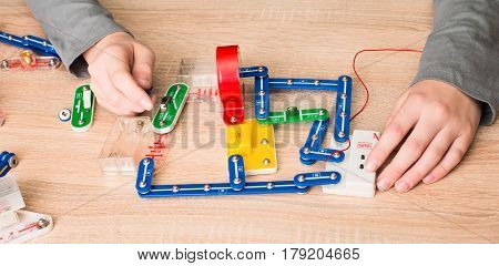 Closeup of hands with parts of electronic constructor. Pre teen boy doing school electronic project in his room at home.
