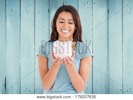 Digital composite of Woman with piggy bank against blue wood panel