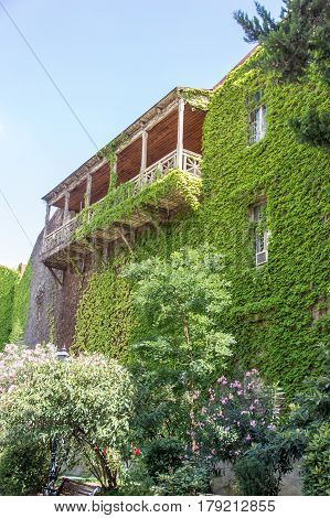 House With A Balcony Overgrown With Grapes
