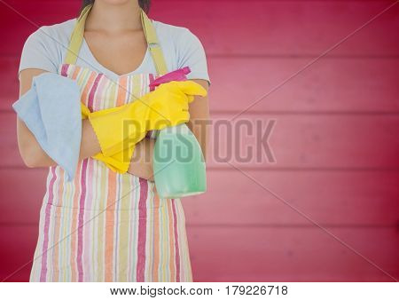 Digital composite of Woman in apron with arms folded and cleaner against blurry pink wood panel