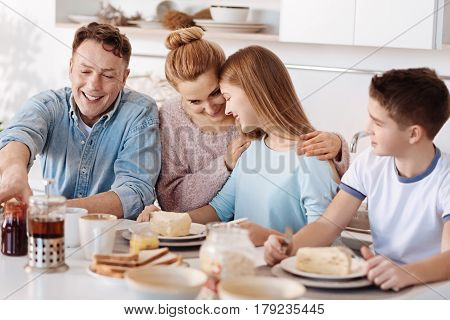 Tasty start of the day. Cheerful delighted friendly family sitting at the table and enjoying their breakfast while expressing happiness