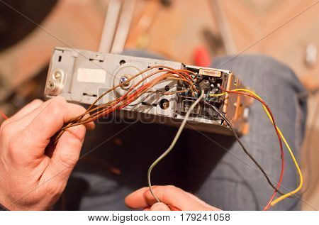 Specialist repair the old car radio cassetter recorder on knee.