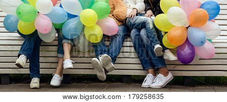 Friends sit on a bench legs close-up birthday many balls