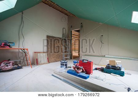 Sheets of drywall parts of scaffolding handle tools and construction material in the room of apartment during on the remodeling renovation and construction