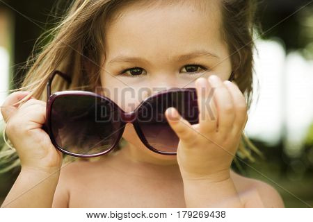 The little girl wears a large adult sunglasses, Asian