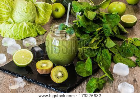 Detox diet. Green smoothie with fruits and vegetables on wooden dark background.