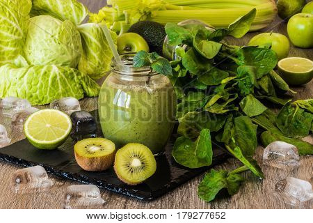 Detox diet. Green smoothie with fruits and vegetables on wooden dark background.