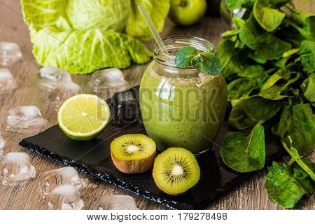 Detox diet. Green smoothie with fruits and vegetables on wooden dark background.