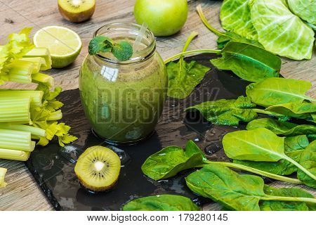 Detox diet. Green smoothie with fruits and vegetables on wooden dark background.