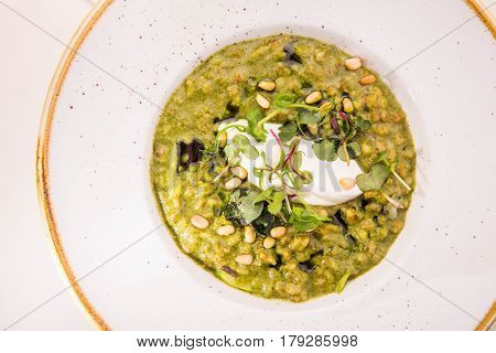 Orzotto with goat cheese and spinach in a round plate on a white cloth