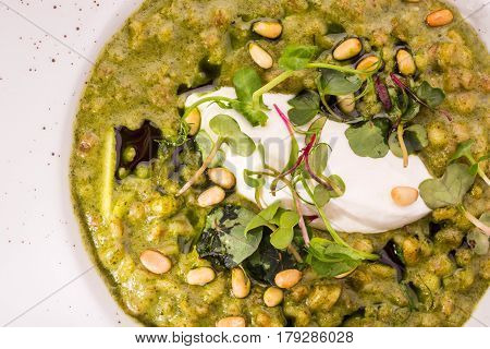 Orzotto with goat cheese and spinach with greens and pine nuts. Top view