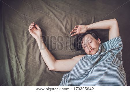 Beautiful Young Man Lying Down In Bed And Sleeping, Top View. Do Not Get Enough Sleep Concept