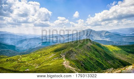 Early morning sun rays illuminate the dawn beautiful Carpathian landscape in the mist on the background of ancient trees are blooming field of summer