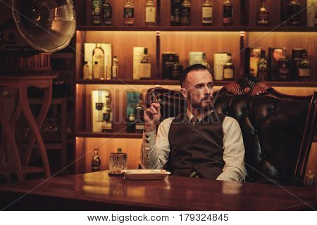 Confident upper class man smoking cigar in gentlemen's club