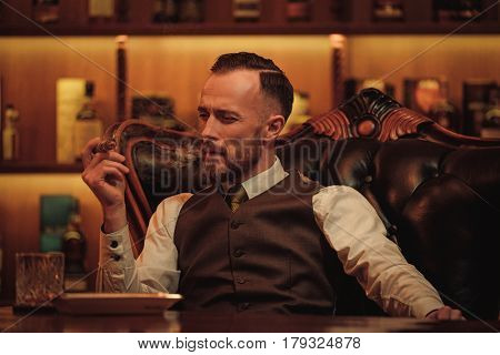 Confident upper class man smoking cigar in gentlemen's club