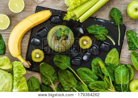 Detox diet. Green smoothie with fruits and vegetables on wooden dark background.