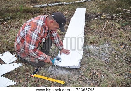 CHERNIVTSI, UKRAINE - APRIL 03, 2017: Contractor Cutting Soffit Board before Installation.Soffit and Fascia Installation.