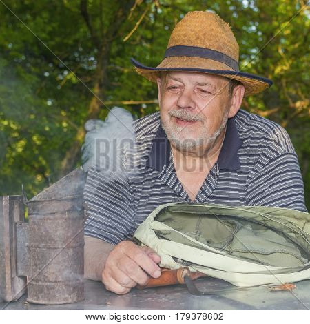 Outdoor portrait of positive elderly man bee-keeper wearing straw hat