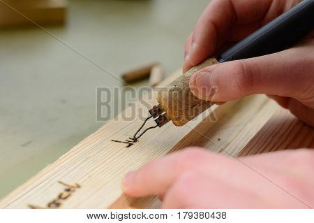 poker work with a fire-mint - close-up pyrography brand painting