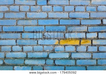 Brick wall texture painted blue with yellow spot in front of viewer