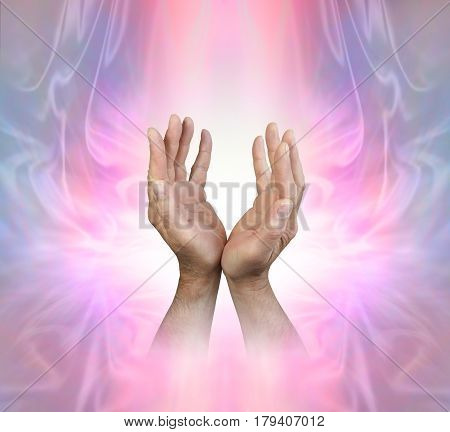 Male hands sensing Feminine Energy Field - male hands reaching up into a pink stream of light on a beautiful ethereal Angelic energy background with copy space