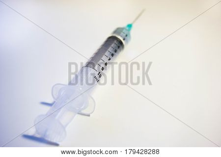 A green tipped syinge containing 2ml of water at a low angle