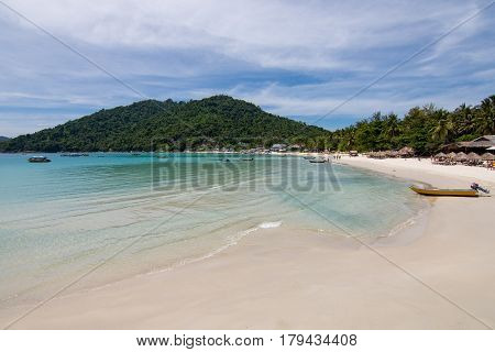 Paradise Beach View With Huts And Small Boat And A Forested Hill Background. Perhentian Kecil, Malay