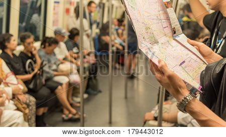 Tourist looks and trying to search location on map inside a MRT subway train runs in Bangkok. Many people in Bangkok used subway to save time.