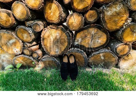 Groom shoes on the grass under a pile of logs