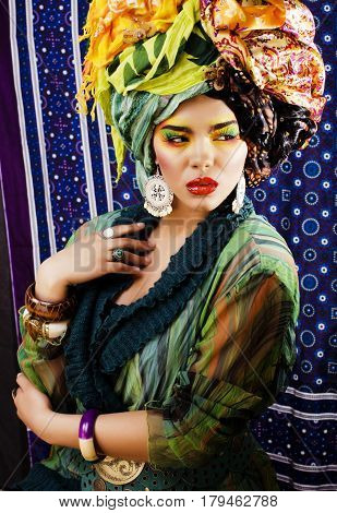 beauty bright woman with creative bright make up, many shawls on head like cubian, ethno look closeup