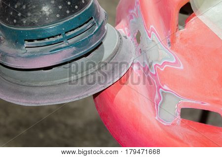 Work polishes the car body component preparation before painting.