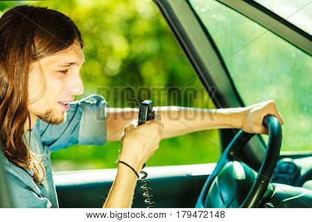 Comunication talking while drive auto walkie talkie concept. Young man driving car using cb radio having fun