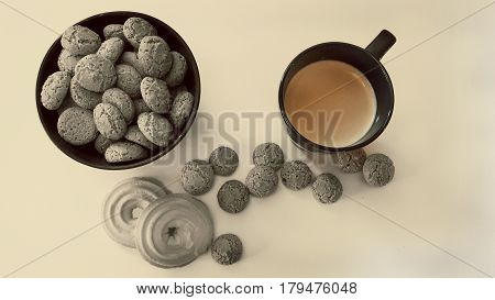 The view from the top. A plate of macaroons and a Cup of coffee on the table among the scattered cookies. Filter the black-and-white focus.