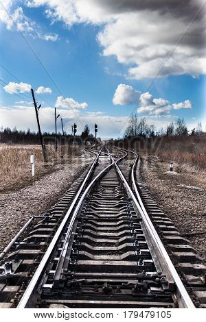 Railway bifurcation in north-west of russia in early spring. Blue sky with white clouds. A very cold windy day.