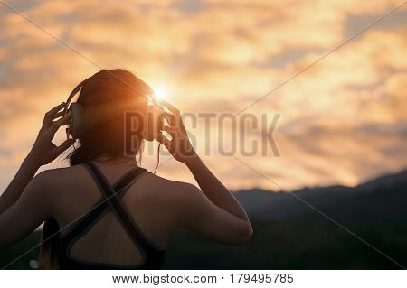 young fitness woman waering headphones at sunrise moutain. relax and healthy conecpt.