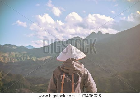 Alone traveler with Nonla hat at peak mountain background Sapa Vietnam travel concept.