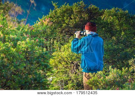Young green coat man taking photograph by digital camera around Kawah ijen valcano at sunrise East java Indonesia