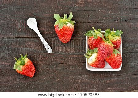 Strawberry fruit on wood background. Forest fruit in white idaeus and spoon. Delicious fresh berries.