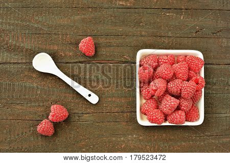 Raspberry fruit on wood background. Forest fruit in white idaeus and spoon. Delicious fresh berries.