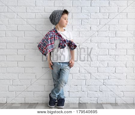 Cute stylish boy near light brick wall