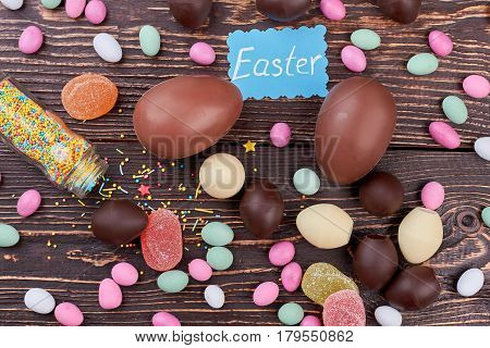 Easter card and scattered sweets. Candies on dark wood background. Homemade Easter candy recipes.